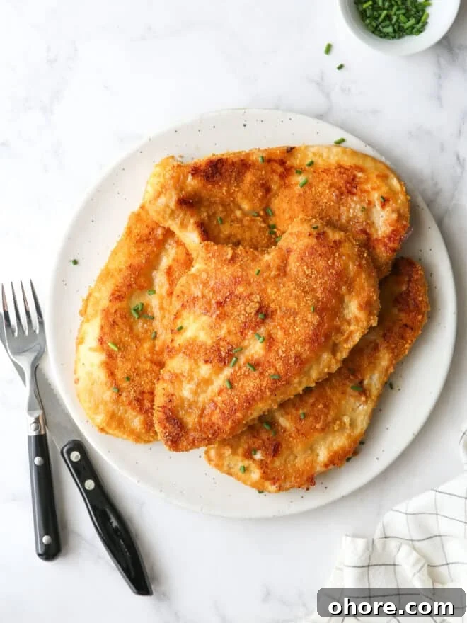 Crispy Oven-Fried Chicken Recipe: Juicy, Golden, and Tender 2 oven fried chicken piled on a plate with chives