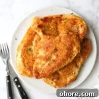 Crispy Oven-Fried Chicken Recipe: Juicy, Golden, and Tender 15 oven fried chicken piled on a plate with chives