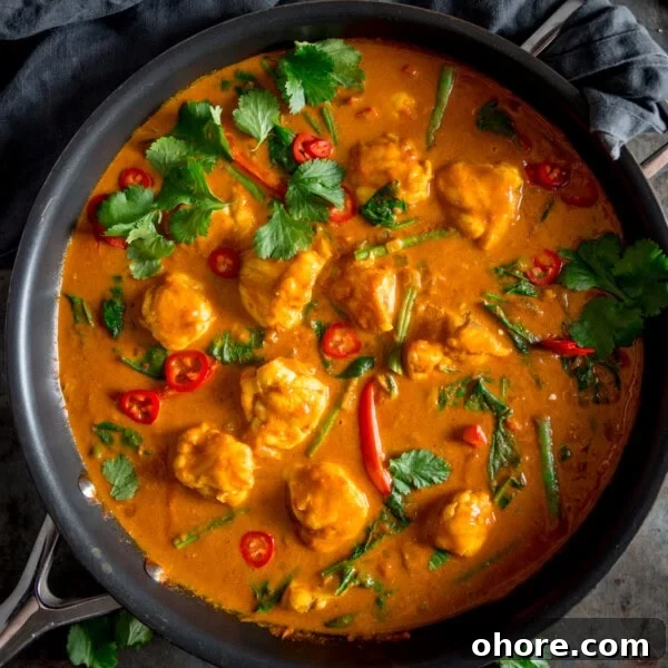 A square overhead shot of Monkfish Coconut Curry in a grey pan, topped with coriander.