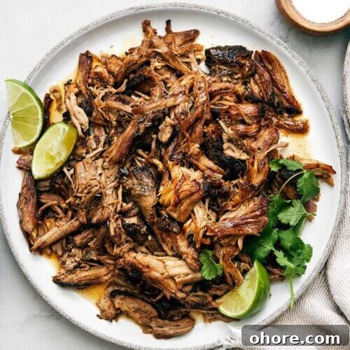 Carnitas on a plate next to tortillas.