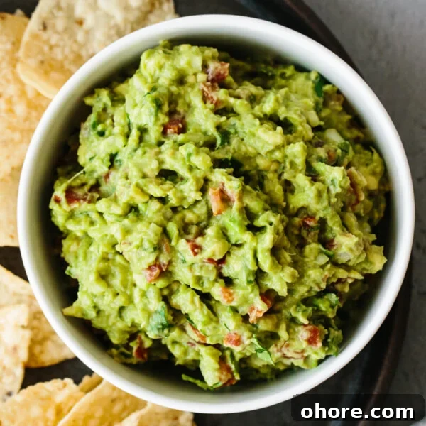 Guacamole recipe in a bowl next to tortilla chips.