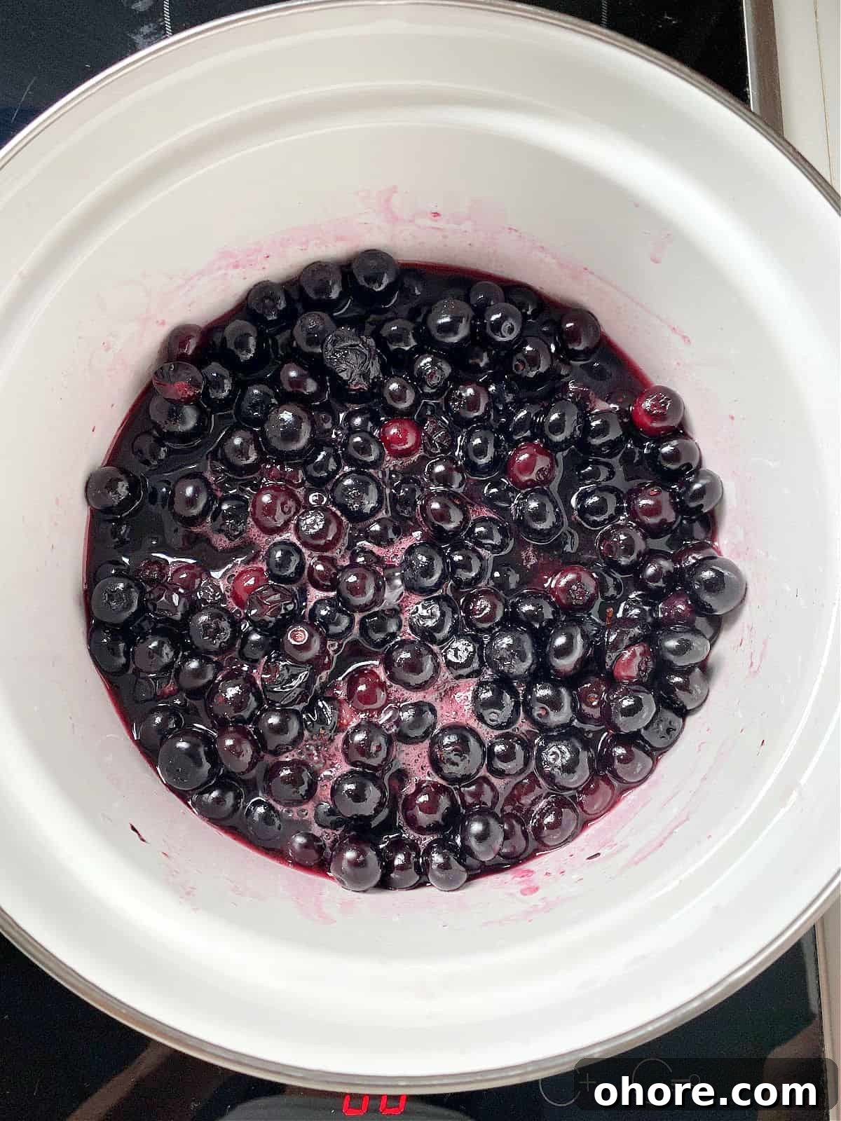 Blueberry Compote Recipe: Simple Homemade Blueberry Sauce 5 White saucepan with blueberries simmering in sugar syrup.