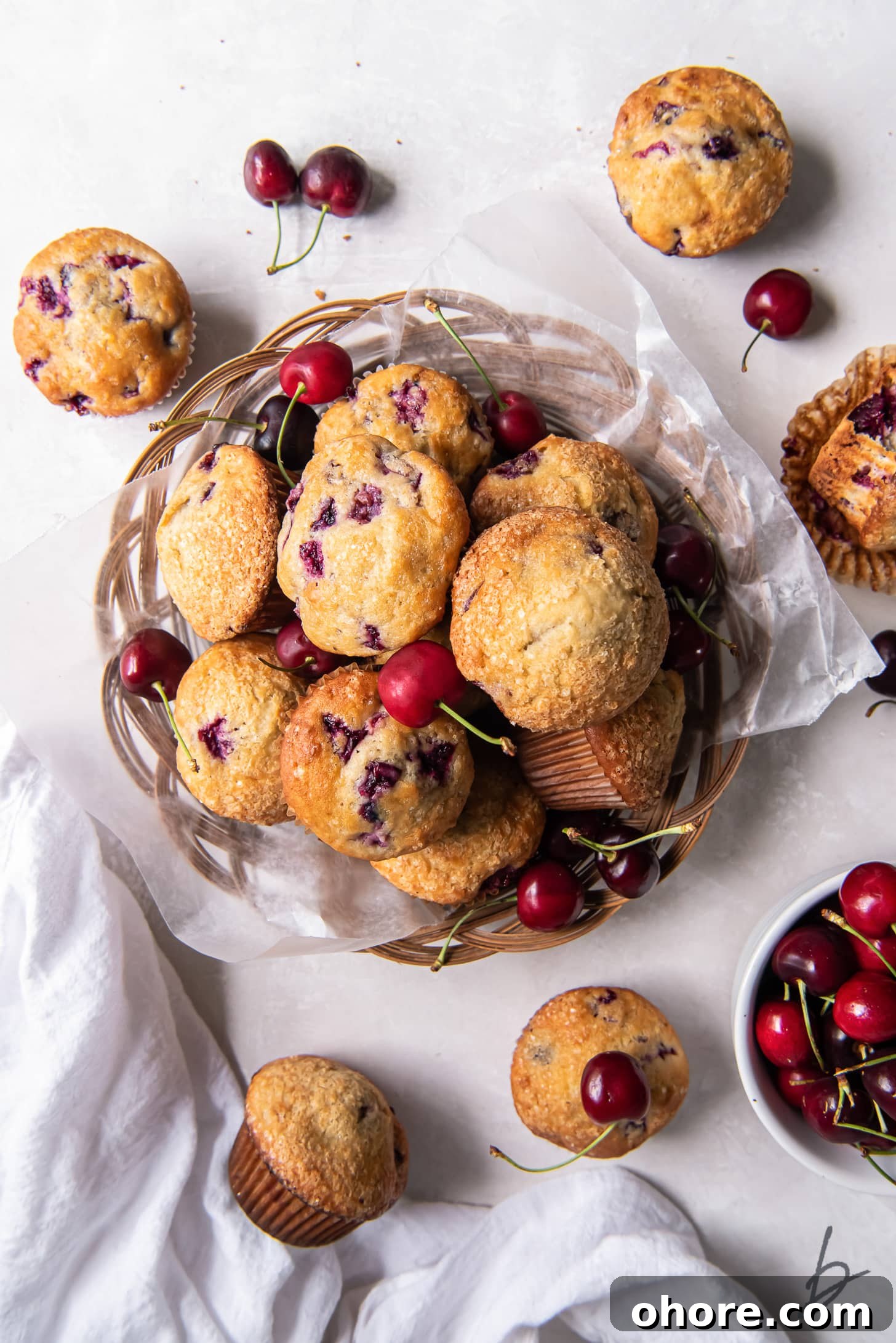 Cherry Almond Muffins: Homemade Cherry Muffin Recipe with Almond Extract 5 pile of cherry muffins on parchment paper in a basket next to a few more muffins