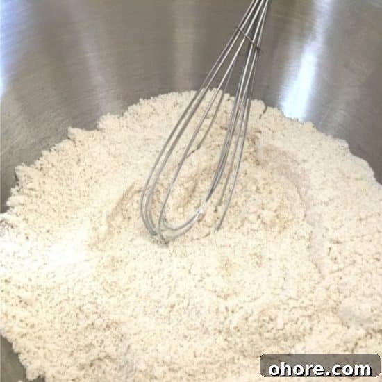 Using a whisk to mix the dry ingredients in the mixing bowl.