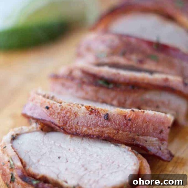Juicy Smoked Pork Loin Recipe for Tender, Flavorful Results 14 Bacon wrapped pork tenderloin cut into slices on wood cutting board with cilantro and lime garnish