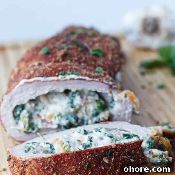 Juicy Smoked Pork Loin Recipe for Tender, Flavorful Results 15 sliced stuffed pork tenderloin with cajun rub and twine holding it together, cheese stuffing, cilantro and garlic cloves sitting on wood