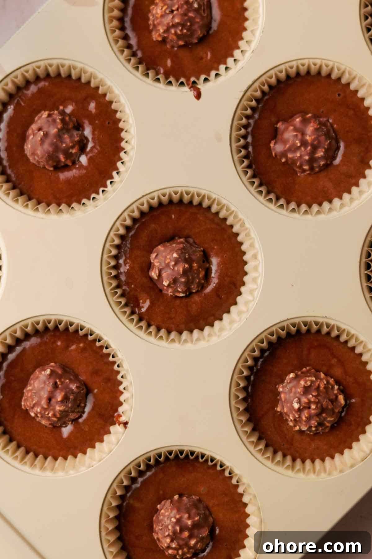 Ferrero Rocher Cupcakes Recipe: Decadent Hazelnut Chocolate Cupcakes 11 chocolate batter in cupcake tins with paper liner and ferrero rocher chocolate in the middle