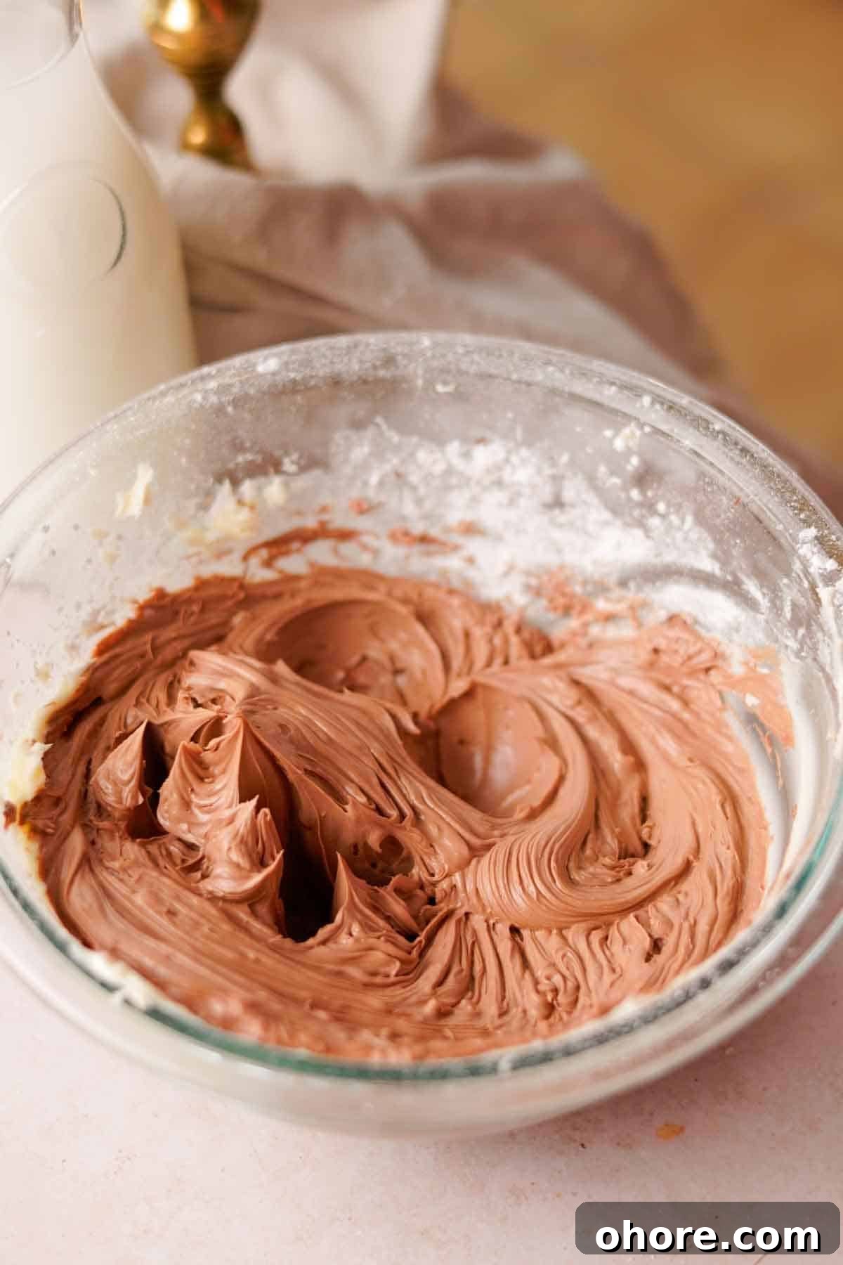 Ferrero Rocher Cupcakes Recipe: Decadent Hazelnut Chocolate Cupcakes 15 creamy light brown nutella frosting in glass bowl with powdered sugar on the sides