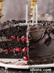 black velvet cake with a piece cut out and black frosting