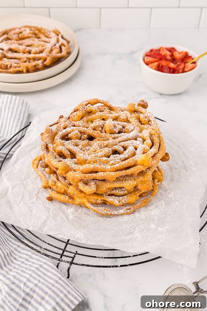 Crispy Homemade Funnel Cake Recipe for Fair-Style Treats 7 A plate of Homemade Funnel Cakes with powdered sugar and strawberries.