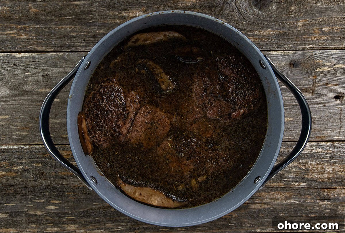 Keto Dutch Oven Pot Roast Recipe — Tender Low-Carb Roast 8 Roast added to the pot with the broth and mushroom mixture.