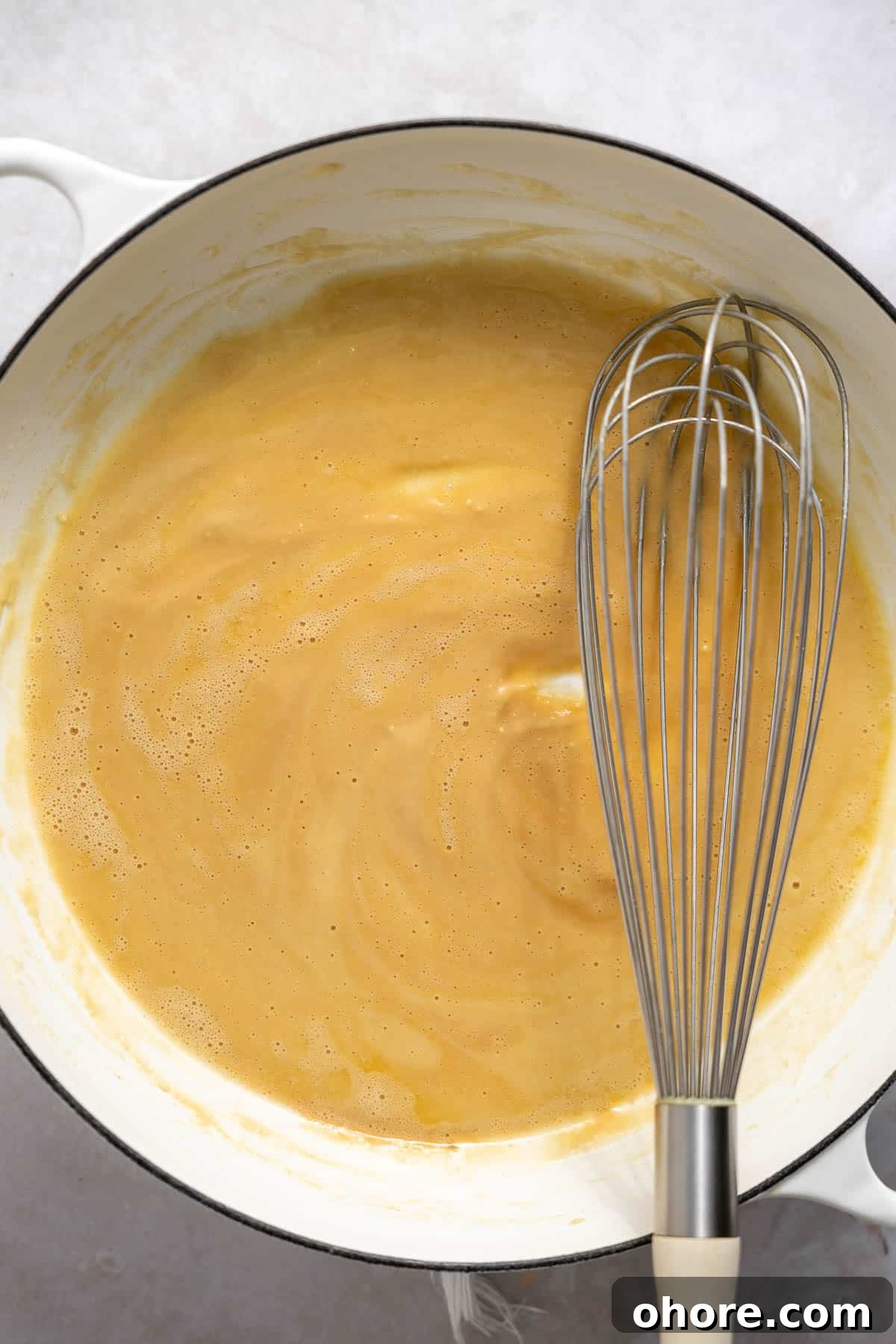 Creamy White Cheddar Macaroni and Cheese Recipe 5 whisking a roux in a saucepan.