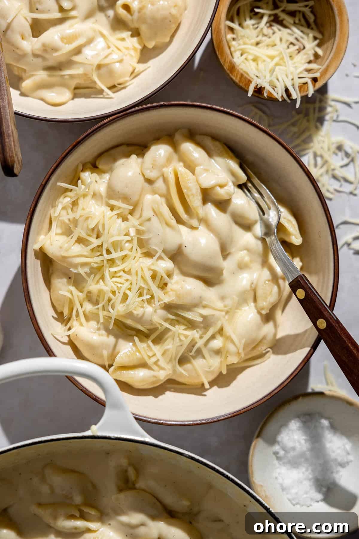 Creamy White Cheddar Macaroni and Cheese Recipe 8 a bowl of white cheddar mac and cheese with shredded cheese on top.