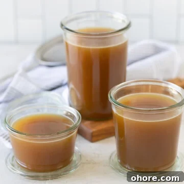 Rich brown roasted turkey broth in glass jars on a kitchen counter.