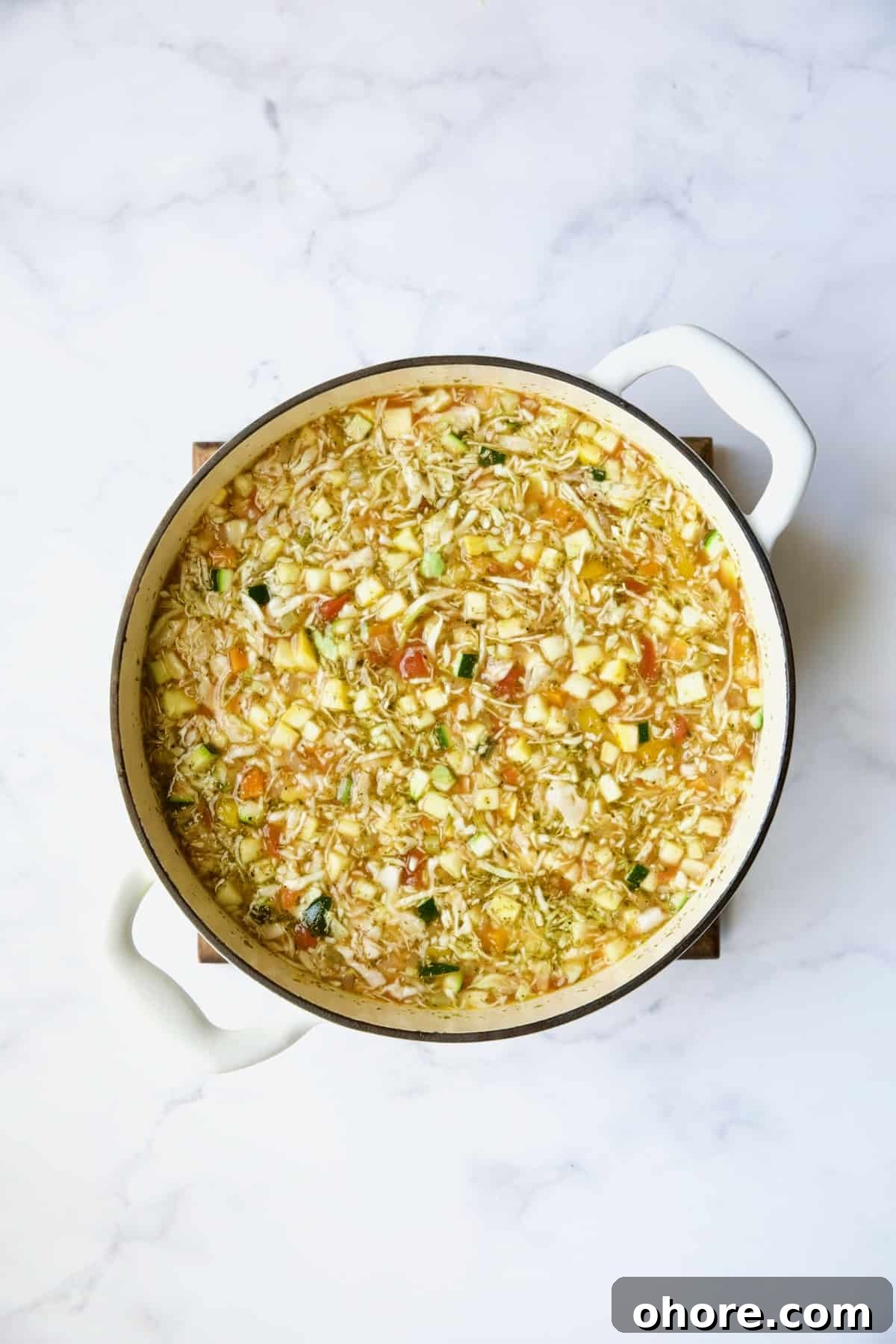 Hearty Vegetable and Barley Soup Recipe for Comforting Meals 7 Vegetables in Dutch oven in broth before being simmered.