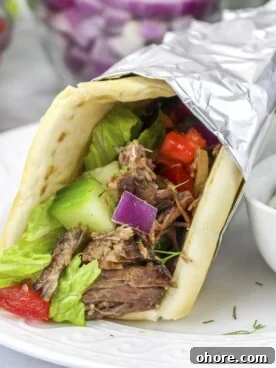 Slow Cooker Beef Gyros Recipe: Tender, Flavorful Greek Sandwiches 10 slow cooker gyros with sauce on side.