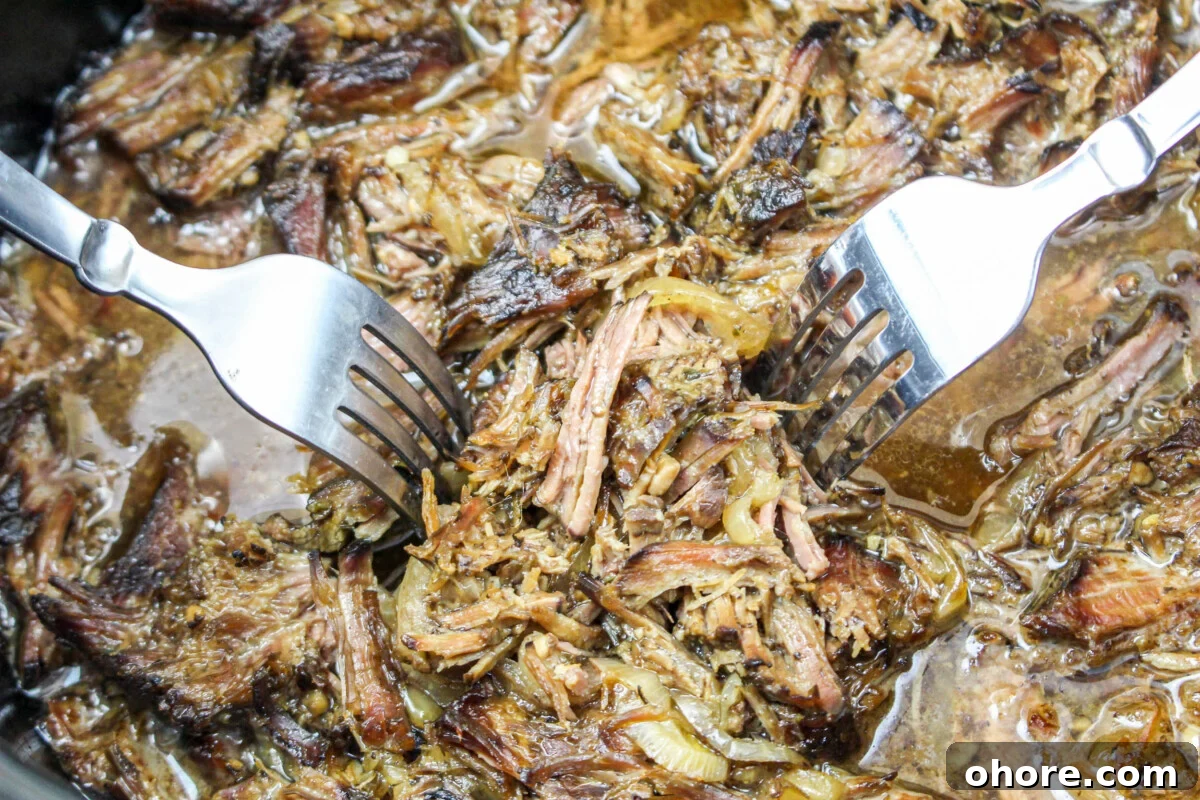 Slow Cooker Beef Gyros Recipe: Tender, Flavorful Greek Sandwiches 7 shredded beef gyro meat in a slow cooker with forks.