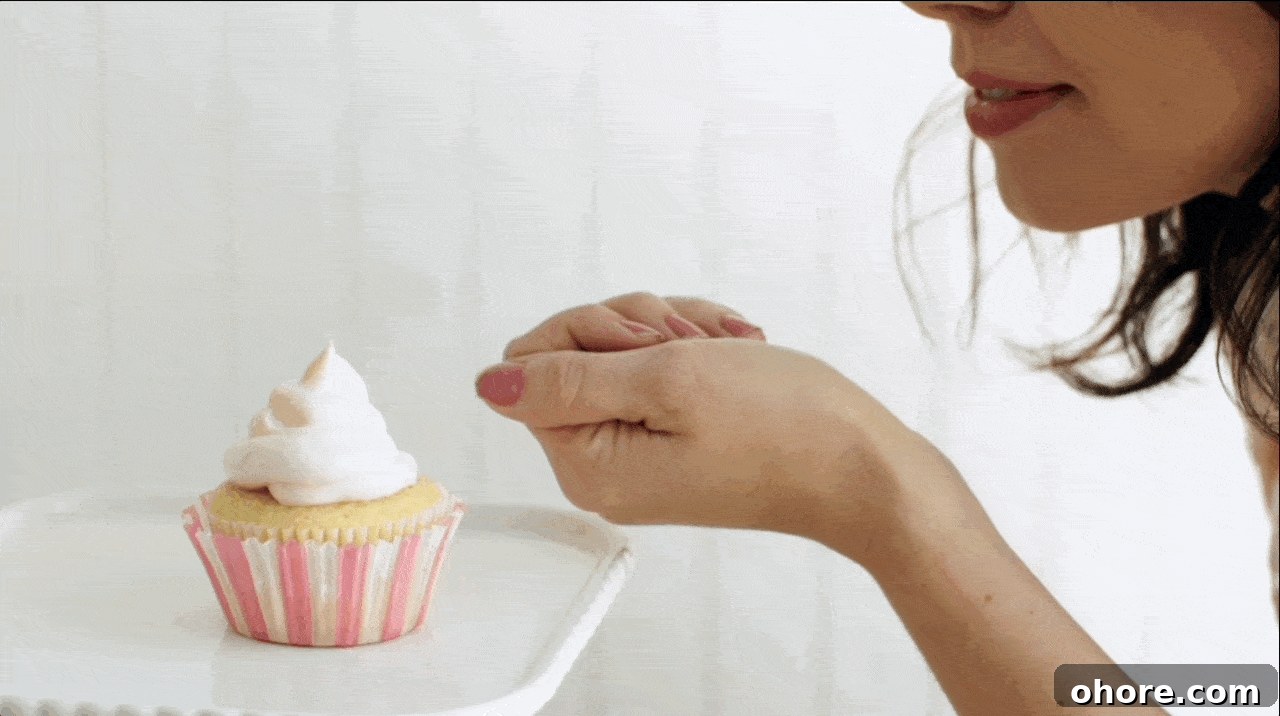 Becky Sue blows edible gold dust from her palm onto the meringue of a cupcake