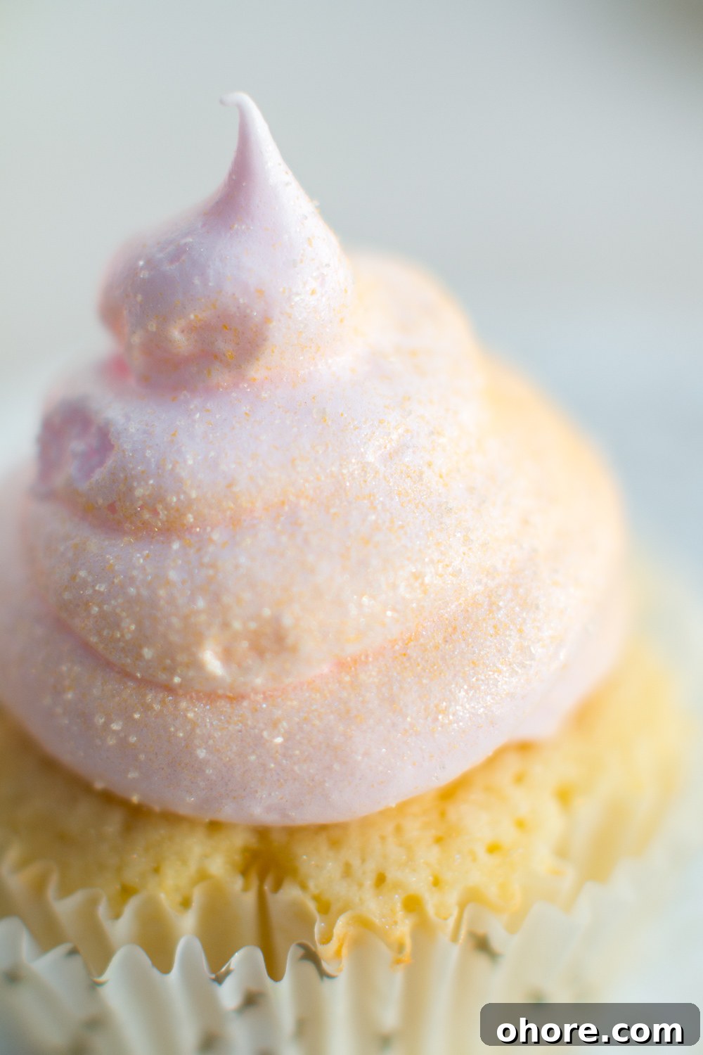 an extreme close up of edible gold dust adorning the meringue swirl atop a pink champagne cupcake