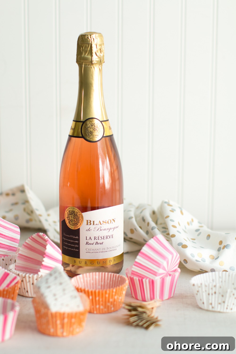 a bottle of pink champagne placed among pink cupcake wrappers