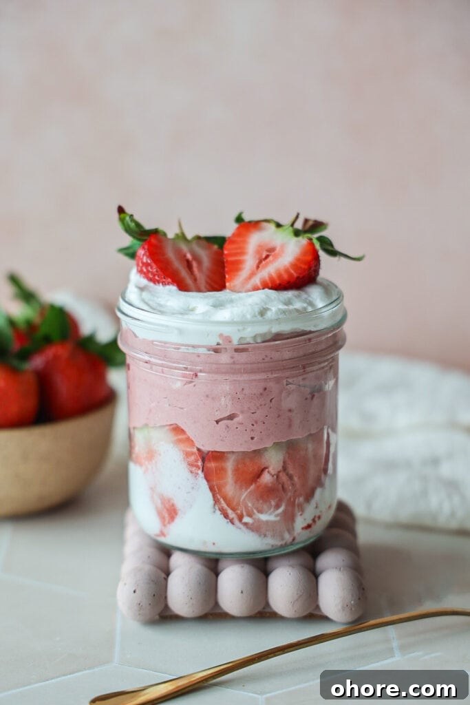 A jar of strawberry yogurt mousse with whipped cream.