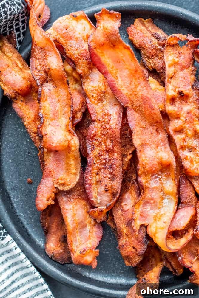 Crispy bacon on a black plate on a black counter.