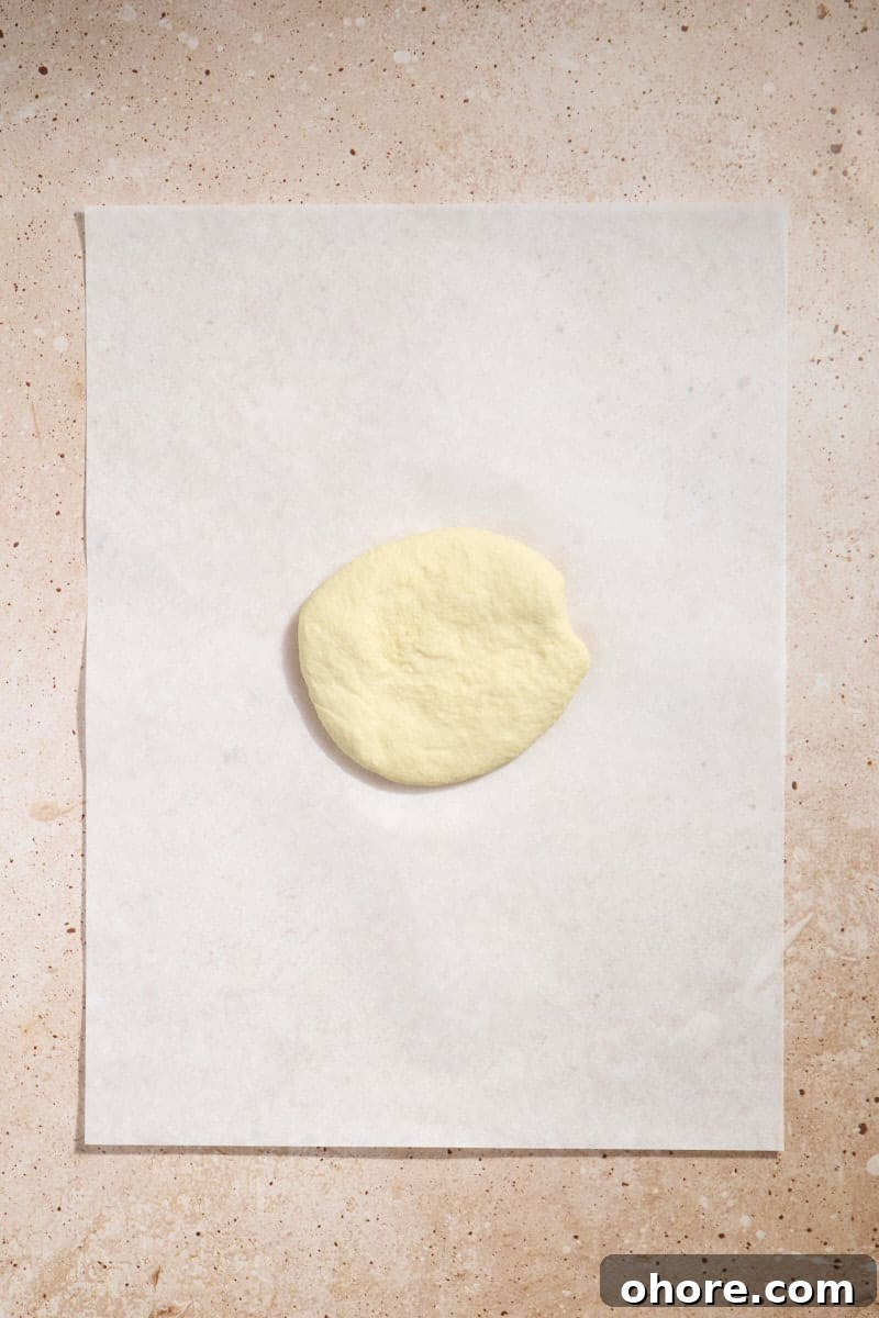 Crispy Sourdough Discard Crackers Recipe for Zero-Waste Snacking 6 Dough in a disk on a piece of parchment paper.