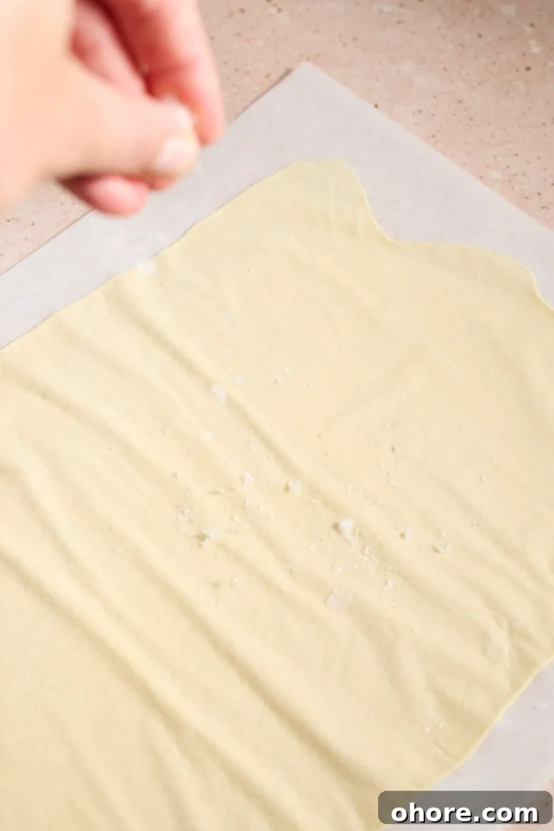 Crispy Sourdough Discard Crackers Recipe for Zero-Waste Snacking 8 Sprinkling salt on the cracker dough.