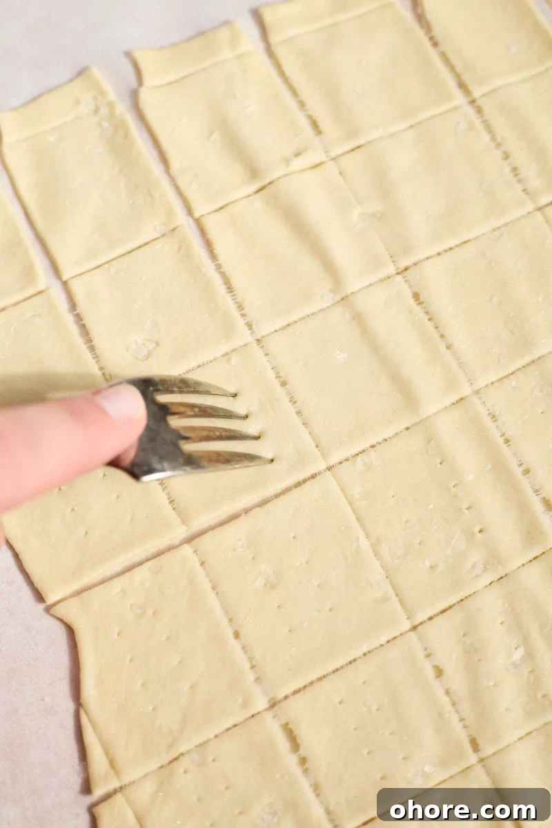 Crispy Sourdough Discard Crackers Recipe for Zero-Waste Snacking 9 A fork poking holes in the Sourdough Discard Crackers.