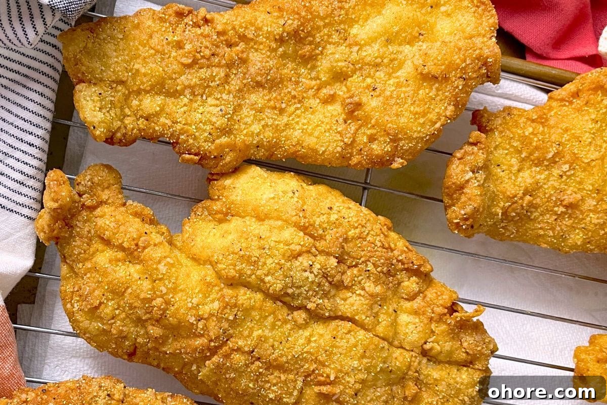 12 Spectacular Seafood Dinners for Meat-Free Weeknight Meals 3 Golden-brown fried fish fillets resting on a cooling rack, showcasing a crunchy texture and savory seasoning.