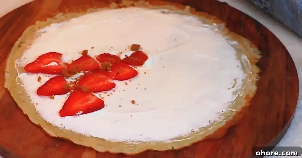 whipped cream, strawberries and crushed biscuits on a crepe