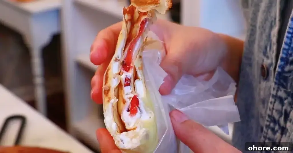 eating a crepe filled with whipped cream and strawberries