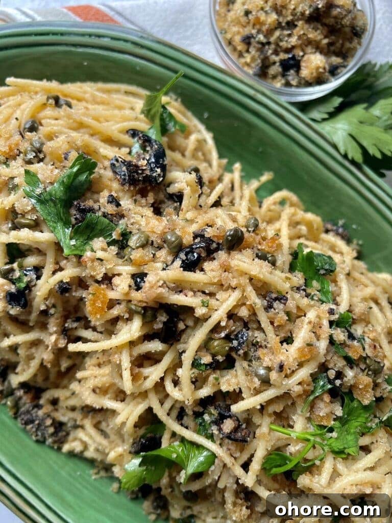 St. Joseph’s Spaghetti with Anchovies and Crispy Breadcrumbs 2 St Joseph's Pasta in green platter with parsley garnish and small bowl of breadcrumbs in background.