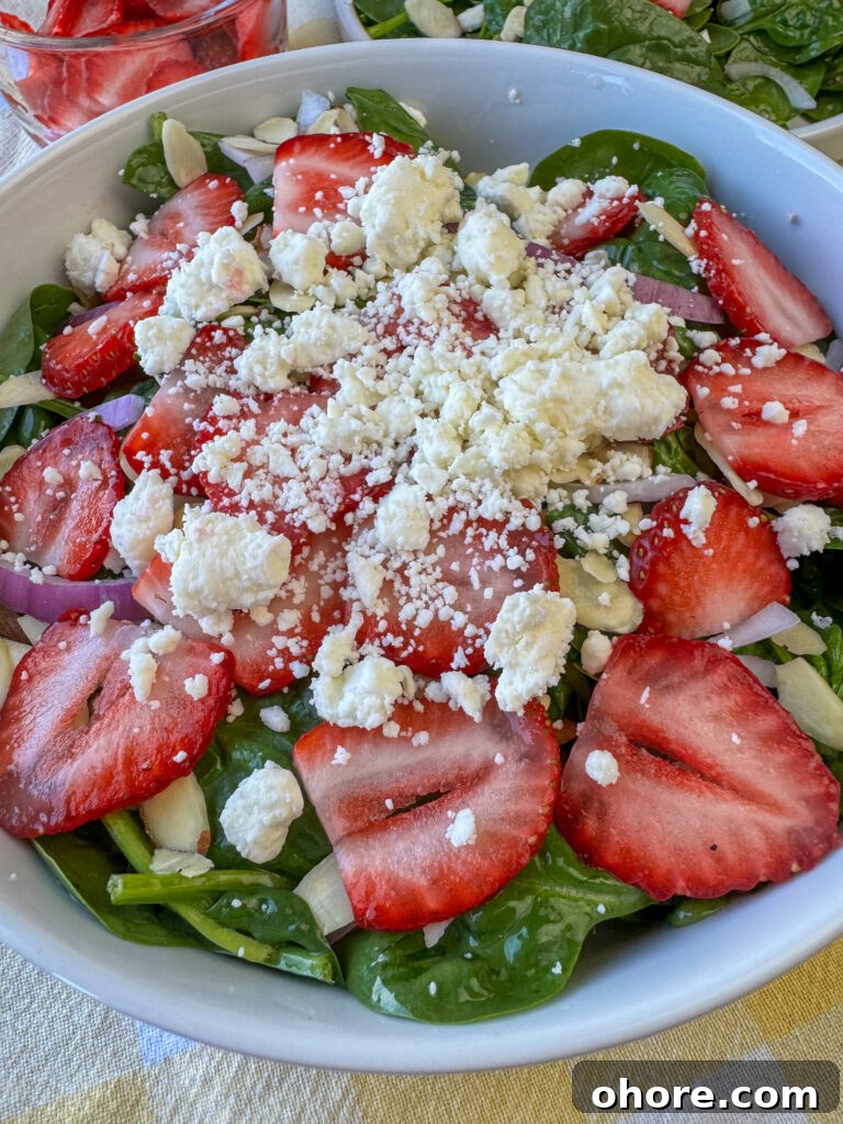 Close up of a spinach and strawberry salad with plenty of feta garnishing the top.