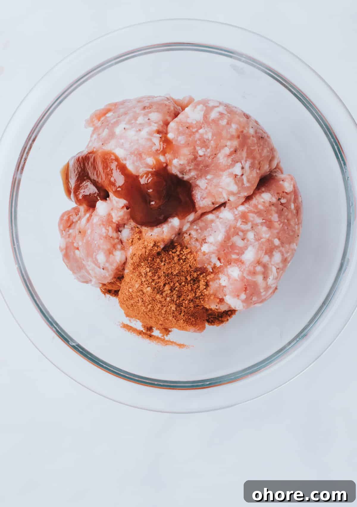 adding spices to bowl of ground sausage