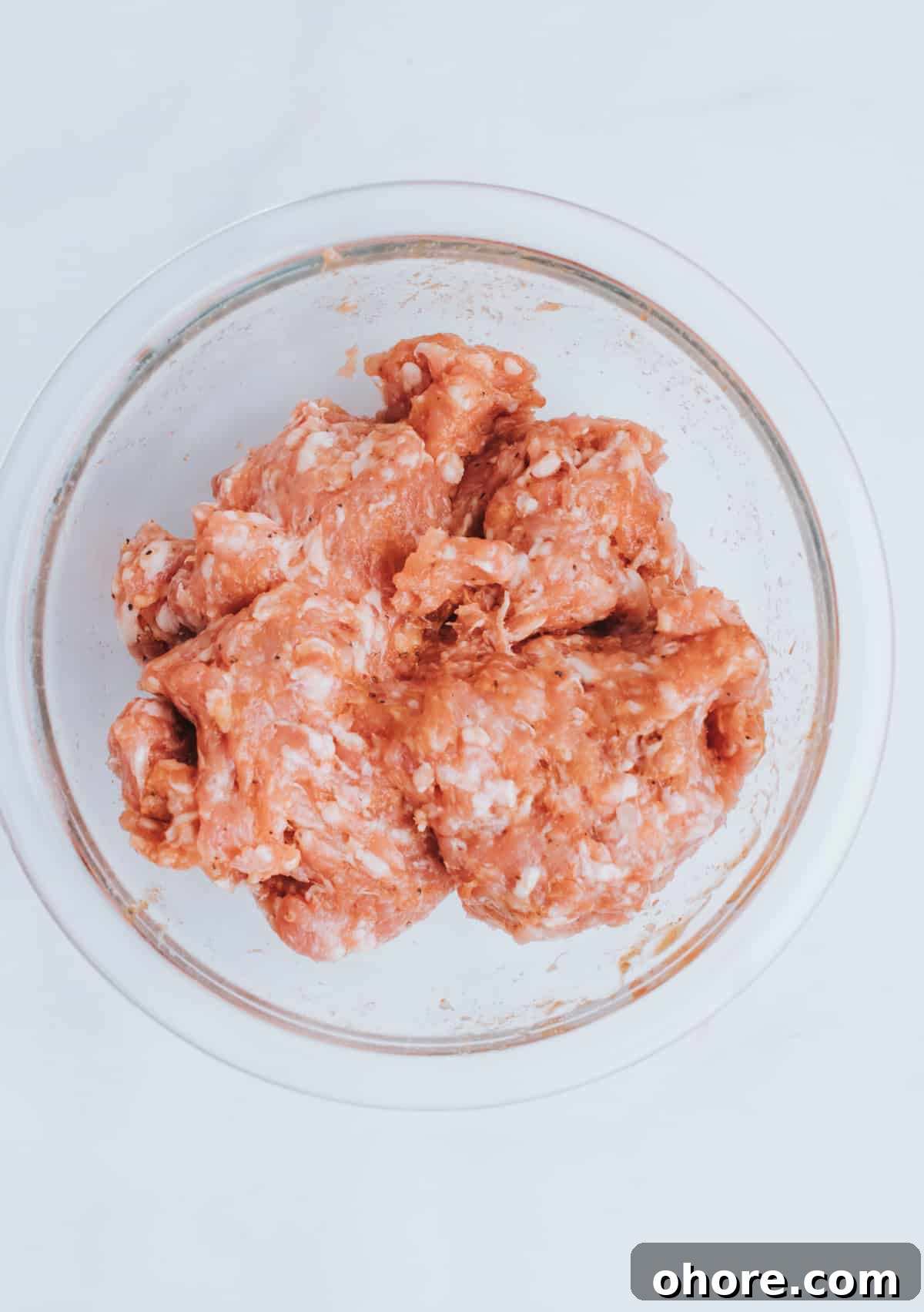 mixing spices to bowl of ground sausage
