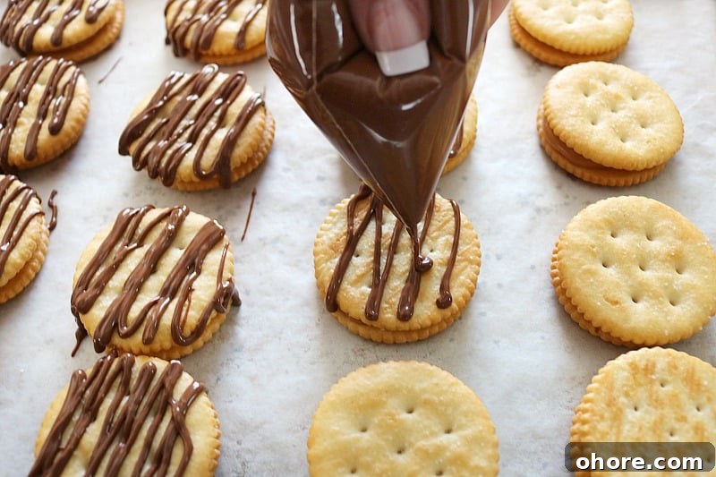 hand drizzling chocolate over crackers. 
