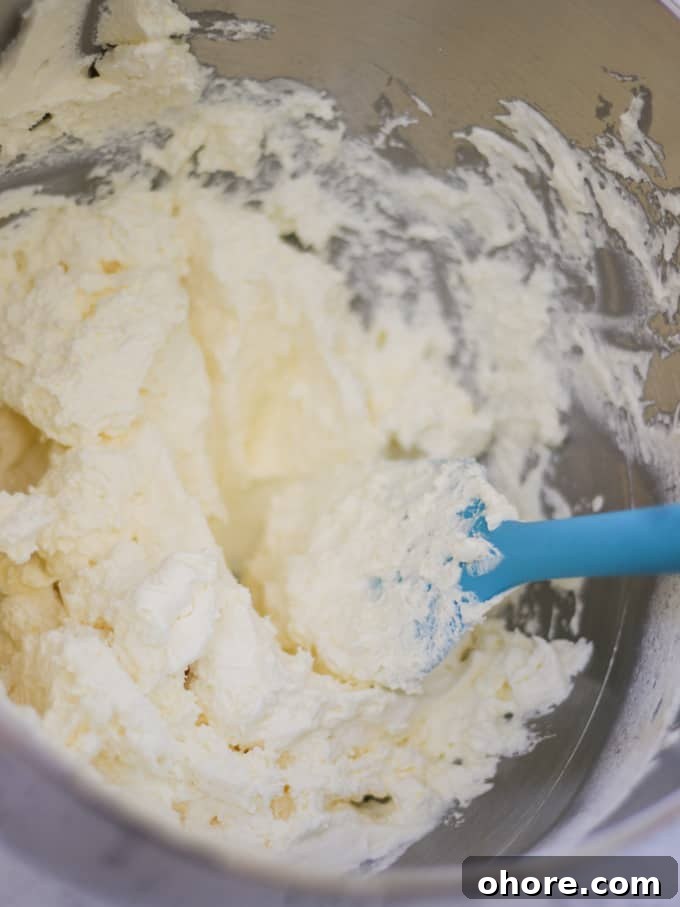 Silver bowl with whipped cream in and a blue spatula.