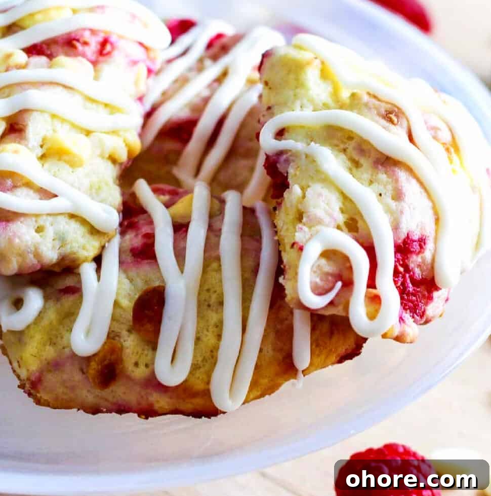 Buttery Raspberry Scones with Lemon Glaze recipe 21 Small white cake plate with homemade raspberry scones studded with white chocolate chips and sweet red raspberries.