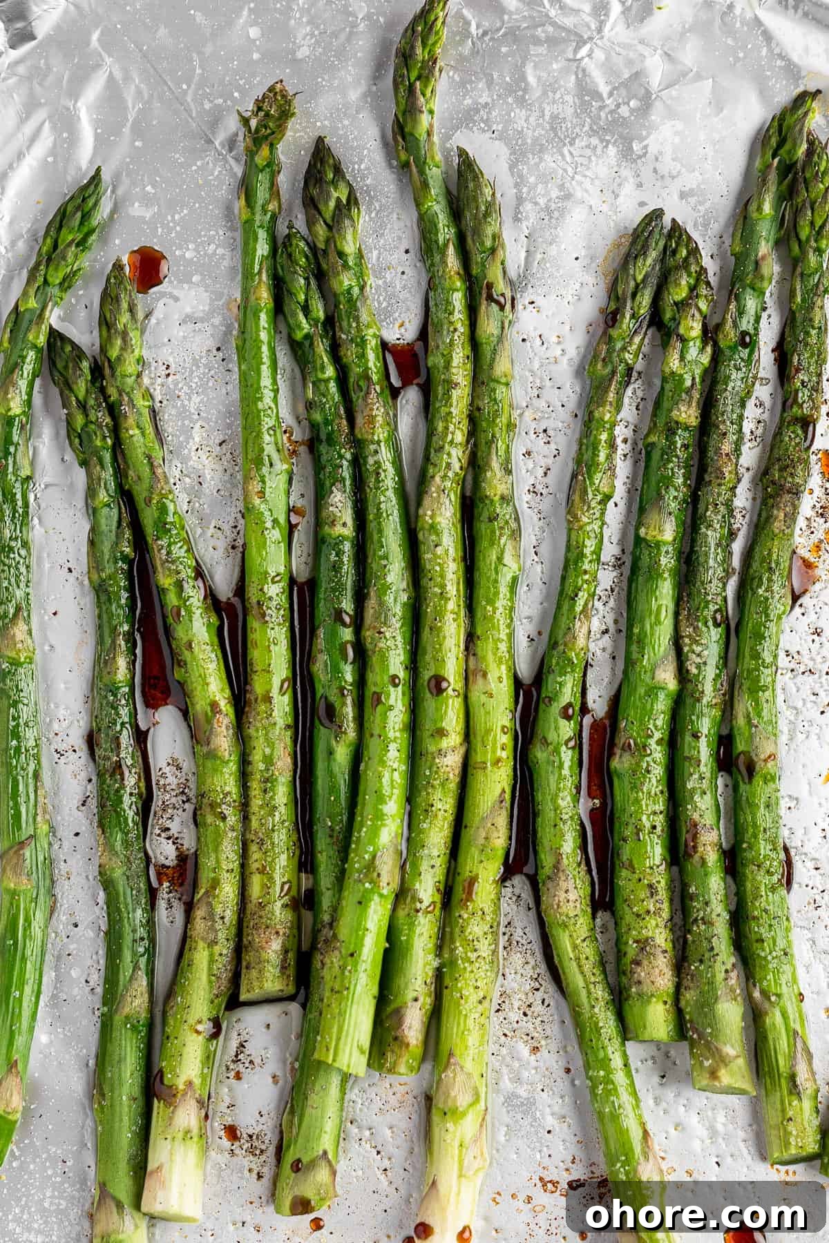 Balsamic-Glazed Asparagus with Garlic and Parmesan 2 A bunch of balsamic glazed asparagus on a tray covered with aluminum folder.