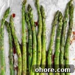 A bunch of balsamic glazes asparagus on an baking tray covered in aluminum foil.