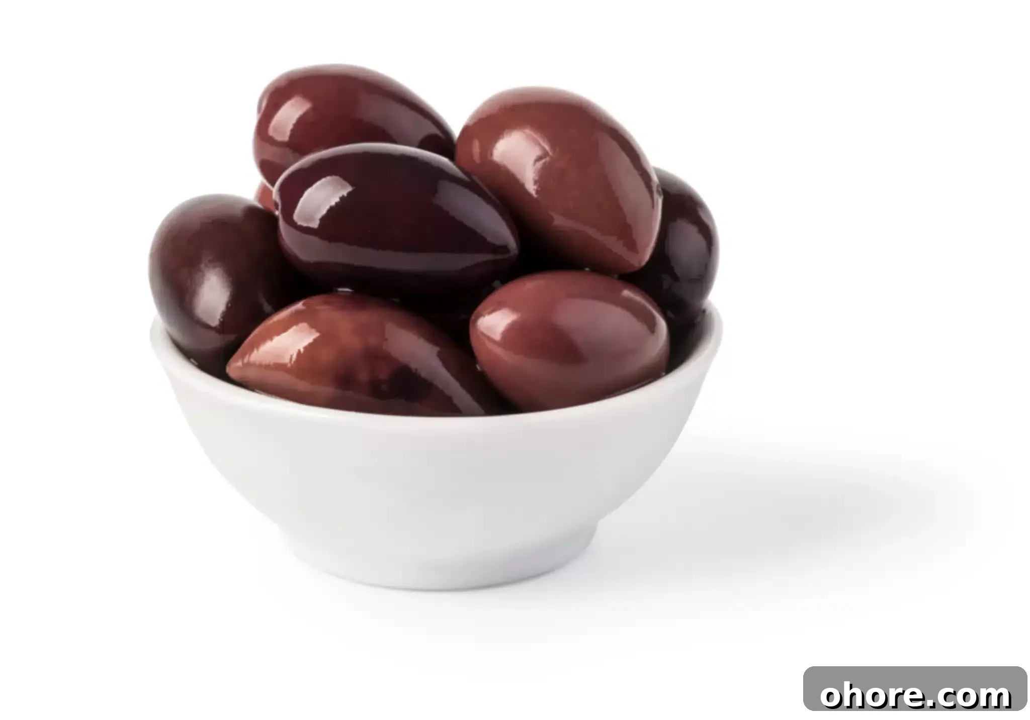 A bowl heaped with Kalamata olives on a white background.