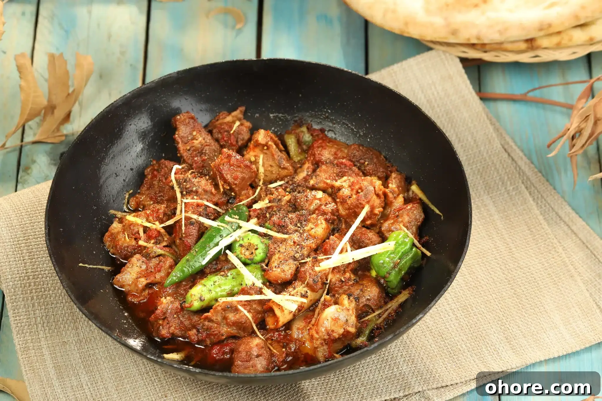 A blue wooden table set up with a wok full of delicious chicken karahi.