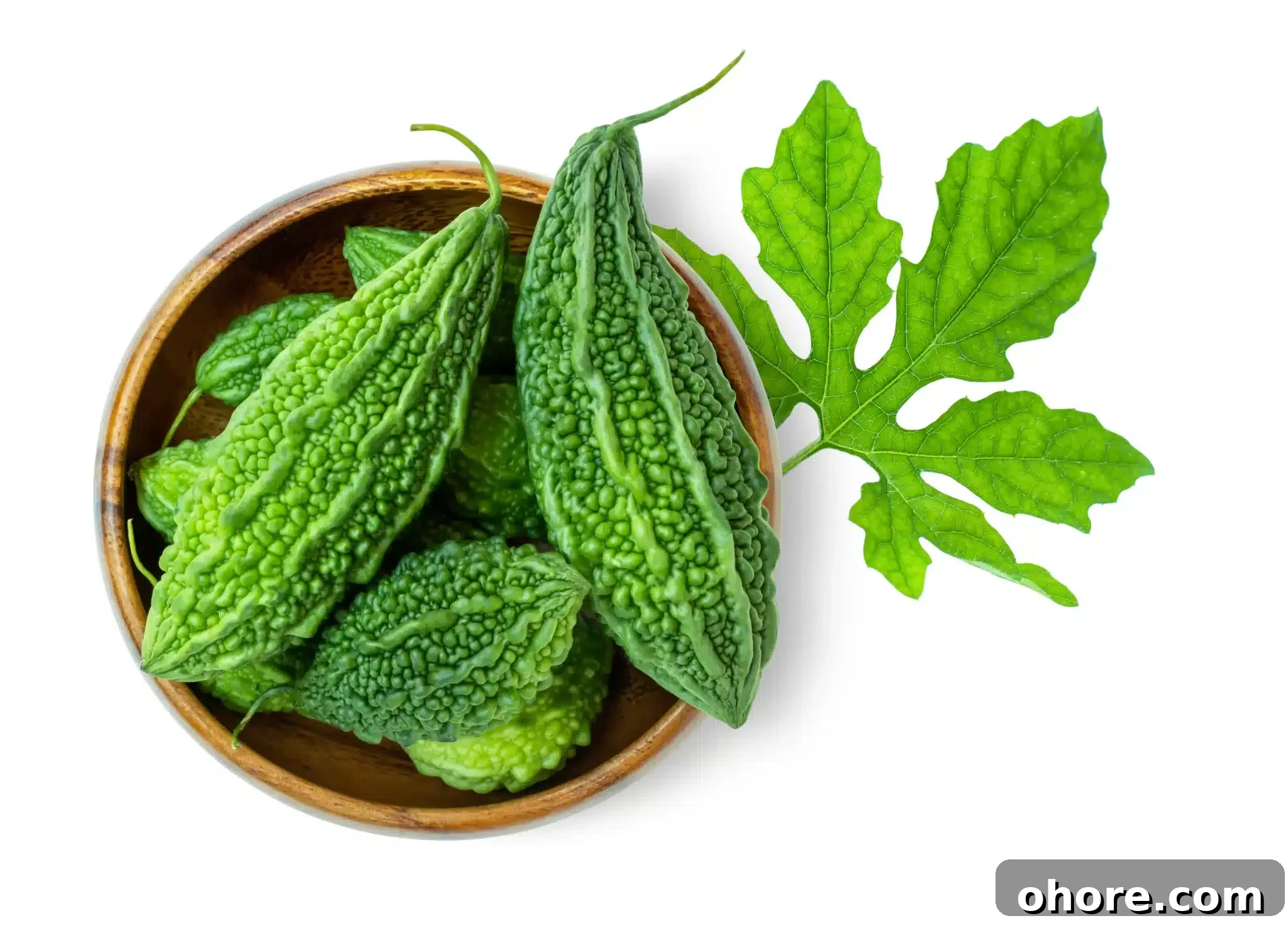 Overhead shot of a bowl containing karelas next to a leaf.