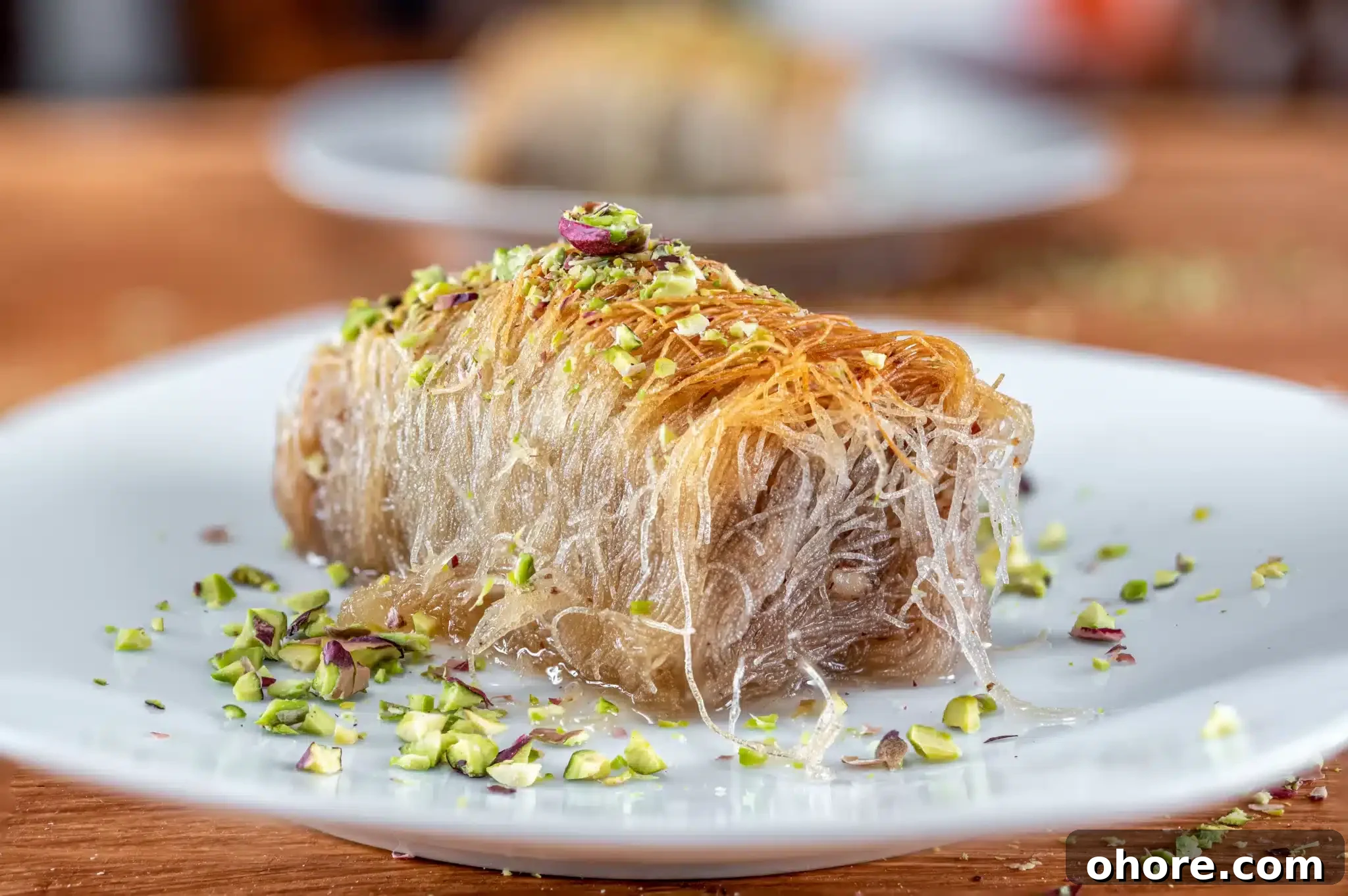 A kataifi served on a plate and sprinkled with pistachio.