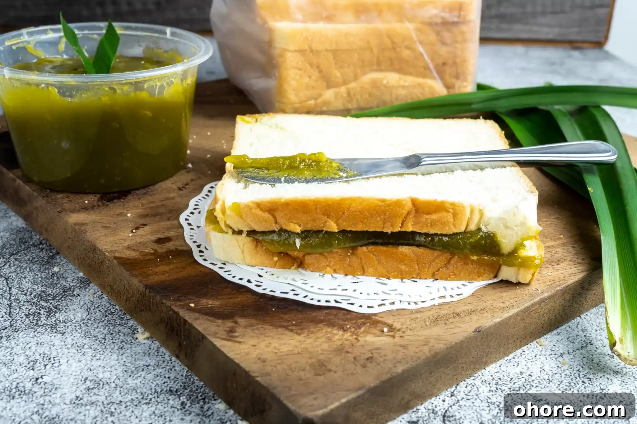 A chopping board holding a jar of kaya and a kaya toast.