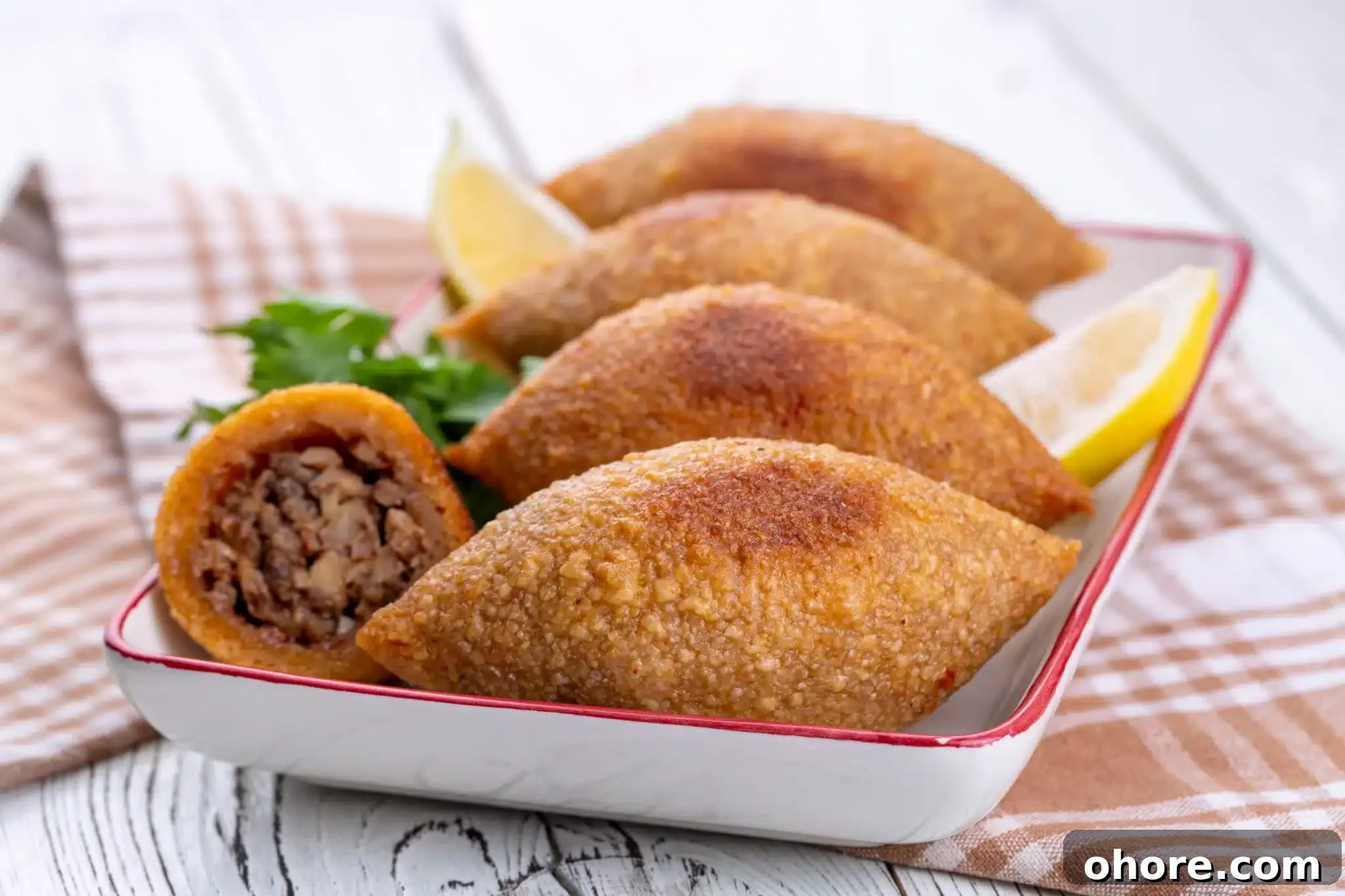 A portion of kibbeh garnished with parsley and lemon slices.