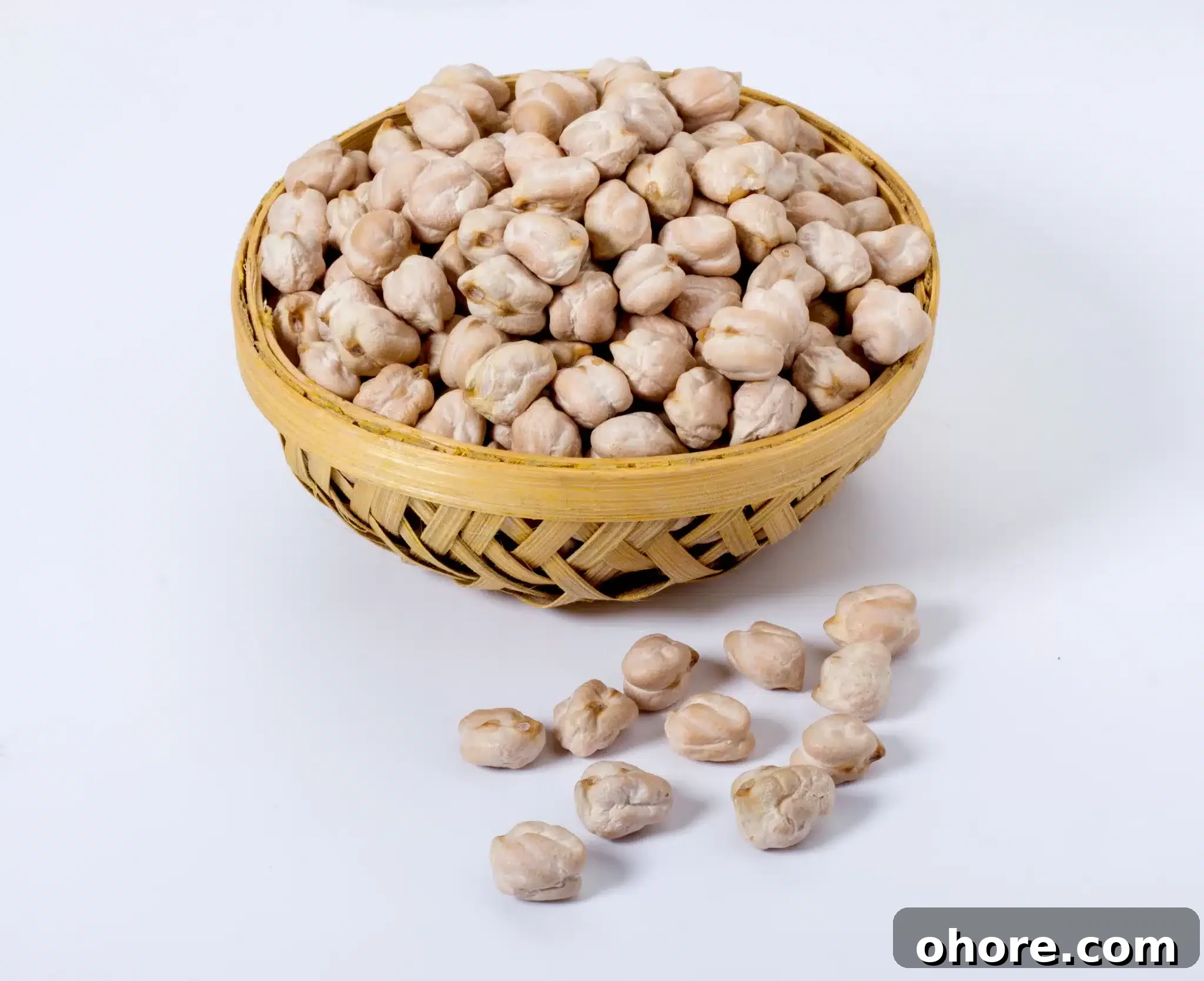 A handcrafted bowl overflowing with kabuli chana chickpeas, with a few scattered nearby.