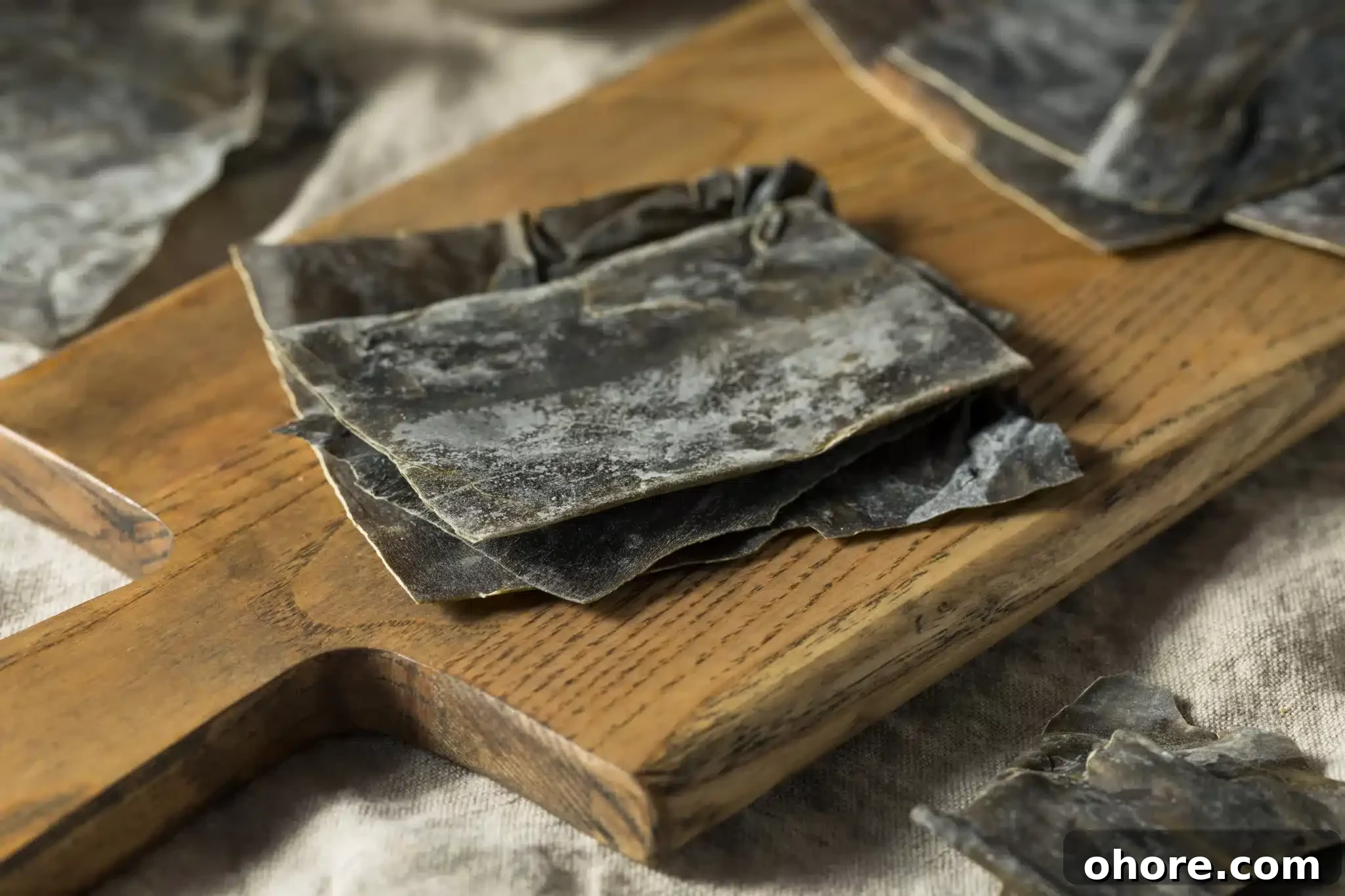A pile of dried kombu sitting on a chopping board.