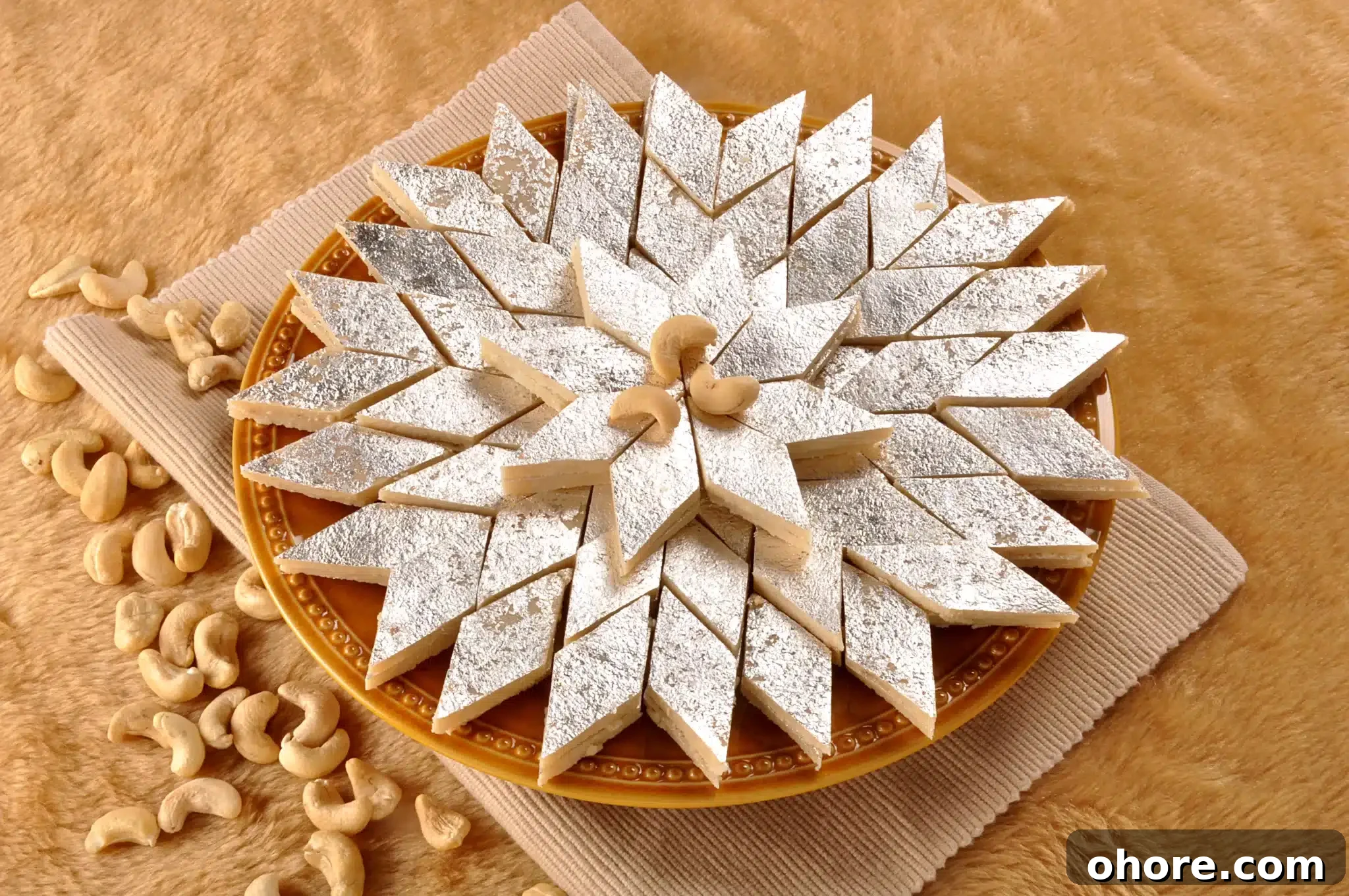 A plate holding several kaju katli portions and a few cashews sprinkled nearby.